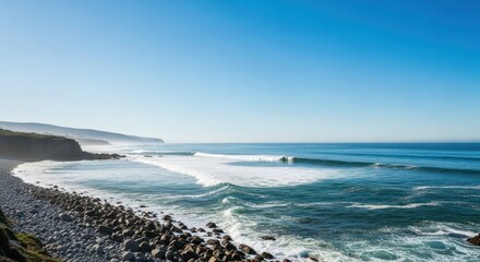 Coastal scene with waves breaking on rocky shore under clear blue sky