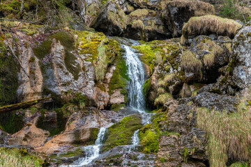 Close-up of small waterfall flowing over moss-covered rocks in alpine forest near Hallstatt, Austria