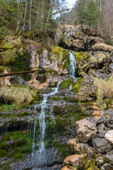 Close-up of small waterfall flowing over moss-covered rocks in alpine forest near Hallstatt, Austria