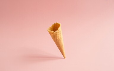 Minimalist concept with a single empty sugar cone for ice cream against a solid pink backdrop, representing summer treats and desserts
