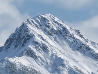 Majestic snow-covered mountain peak towe against a cloudy sky with rugged slopes and icy ridges in a winter landscape