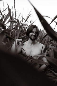 Man among tall corn stalks in field, black and white photography