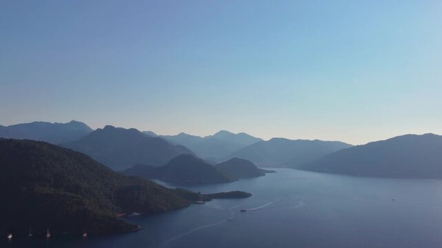 aerial footage showcases the stunning natural beauty of the Turkish Riviera near Marmaris. Crystal clear turquoise waters of secluded bays are framed by lush green, forested mountains under a clear bl