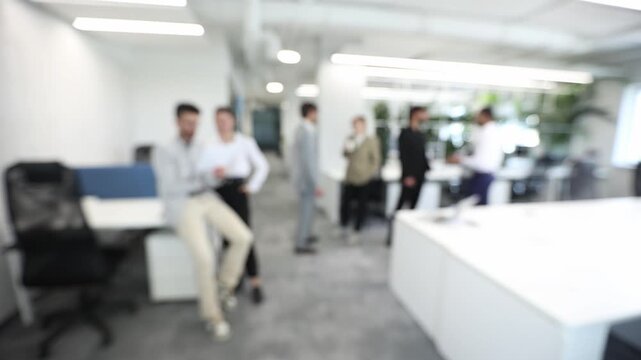 A blurry image of a group of people in a white office