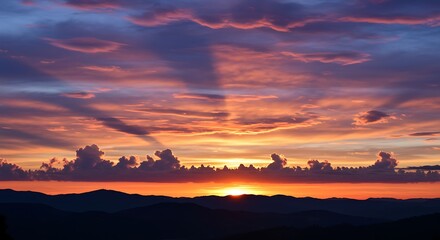 Vibrant sunset over silhouetted mountains with dramatic cloud formations