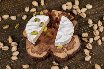 green pistachios and cheese in a white mold, delicious white soft cheese in a mold cut in the center and salted pistachios with and without cracked shells