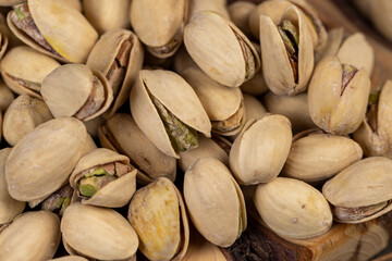 unpeeled pistachio nuts in salt, scattered salted pistachios after roasting with cracked shells