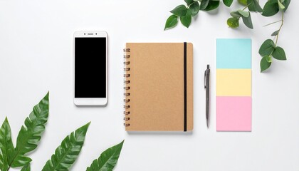 Top view of a smartphone, notebook, pen, and sticky notes arranged with green leaves on a white background