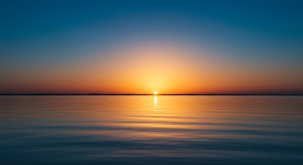 Tranquil sunrise over calm water horizon with vibrant orange and blue hues
