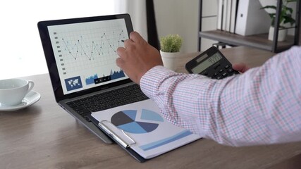 Close-up of accountant analyzing financial report with calculator and laptop in a modern office; budgeting, bookkeeping, and data analytics concept for business content - Powered by Adobe