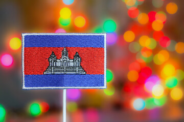 Embroidery Cambodia flag with Angkor Wat symbol in front of colorful bokeh rainbow lights, festive background perfect for New Year celebration and global events.