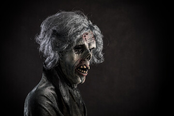 Scary zombie with gray hair over dark background
