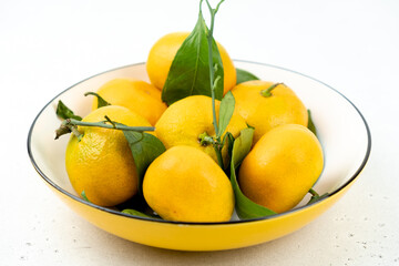 Tangerines in a bowl, light background, close-up, winter fruits.