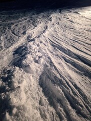 Fototapeta premium Snowy Mountain Terrain with Deep Tracks and Textured Ice Surface in Winter Landscape Under Clear Sky