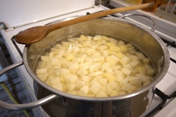 Cubes of raw potato in water inside a cooking pan. Close-up image of homemade preparation for cooking.
