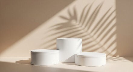 Three white cylindrical pedestals with palm leaf shadow on beige background.