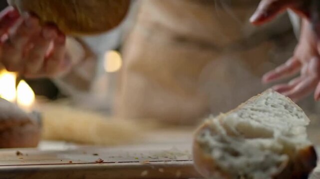 Baker's hands breaking a golden brown, crusty bread loaf 