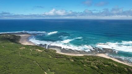 Ocean waves breaking on a white sand beach with turquoise emerald colored water on the coast of Australia