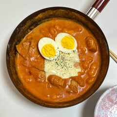 Spicy Korean tteokbokki with chewy rice cakes in a vibrant red sauce, topped with sesame seeds and green onions. A popular street food known for its addictive flavor and satisfying texture.