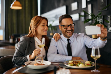 Happy business couple taking selfie during lunch in restaurant.