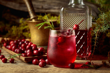 Cranberry cocktail with natural ice and rosemary in frozen glass.