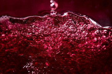  Macro shot of red wine with bubbles in motion.