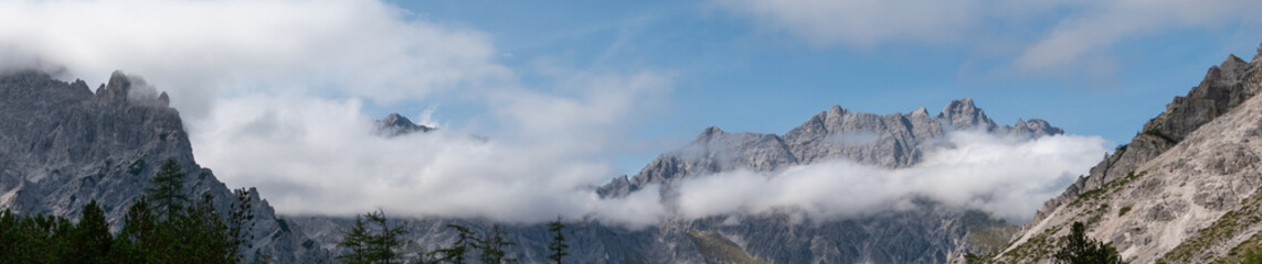 Alpine mountain peaks emerging above a drifting cloud layer