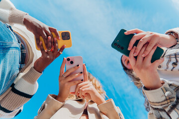 Obraz premium Diverse young friends actively engaging with smartphones. Capturing moments and sharing digital content. Representing youth culture. Social media connection