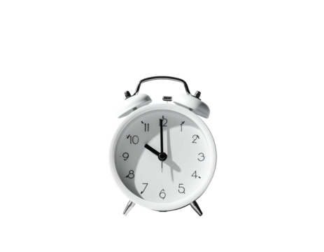White analog alarm clock on a black background; sunlight highlights the dial
