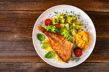Fried atlantic redfish with boiled potatoes and sauerkraut on wooden table. Top view