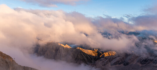 Dramatic alpine cloudscape viewed from the Zugspitze towards the Zugspitzblatt, glowing mountain ridges and rolling clouds at sunrise
