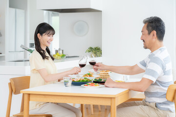 リビングで食事をするミドルの夫婦