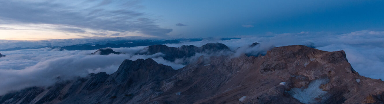 Blue hour view over the remaining ice fields of the Schneeferner Glacier, rugged alpine plateau and dramatic clouds highlighting climate change in the high mountains