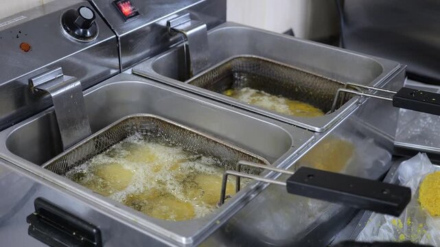 Close-up of a cook putting cutlets and chebureks in boiling oil in a restaurant kitchen. The process of deep-frying food. The concept of fast food and catering.