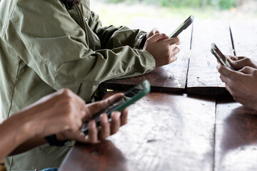 A group of people sitting together but focused on their own smartphones, showing modern lifestyle and digital communication habits