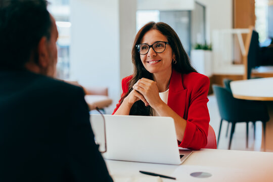 Woman in red jacket engaged in a professional conversation with a colleague