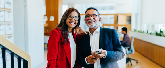 Senior executives smiling confidently during informal meeting in a bright office environment