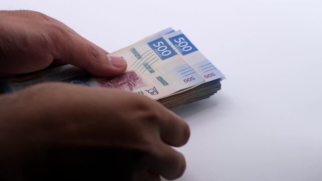 Close up of a man counting pesos Mexicanos. Studio shot