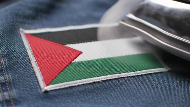 Close-up of a Palestine flag patch being ironed onto denim fabric