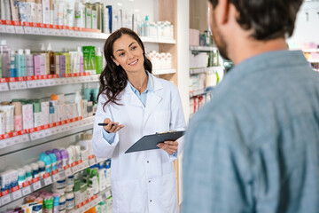 Pharmacist and male patient discussing healthcare products in retail pharmacy