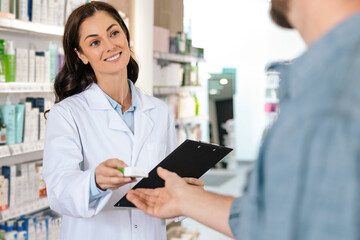 Dark-haired woman pharmacist giving pills to client