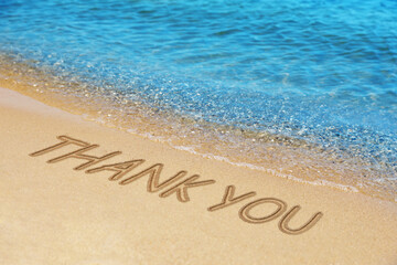 Thank you card design with words written on golden sand