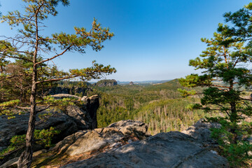 Obraz premium Panoramic view of sandstone cliffs and forested valleys in Saxon Switzerland National Park, Germany, scenic rock formations and green landscape under clear blue sky