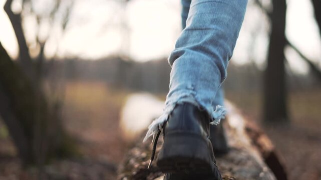 Walk on log balancing with boot, denim leg and ankle visible, steady hiking step along forest trail, nature scene with closeup of sole on bark, emphasis on balance and calm outdoor movement.