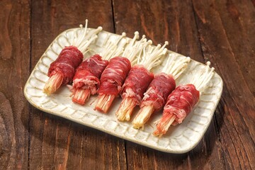 Raw Beef enoki roll is a rolled sheet of beef filled with enoki mushrooms.