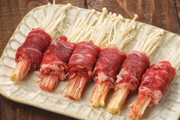 Raw Beef enoki roll is a rolled sheet of beef filled with enoki mushrooms.