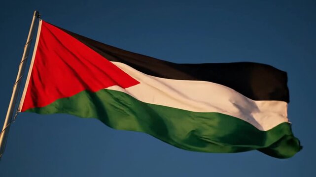 Flag of Palestine waving in the wind against a clear blue sky
