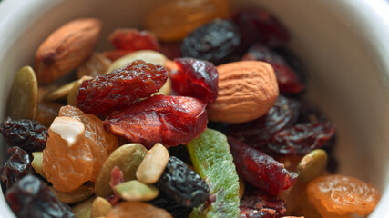 Close up of assorted dried fruits and nuts, including almonds, raisins, cranberries, and seeds in a bowl