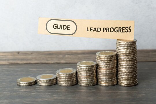 Stacked coins representing financial growth with a guide sign indicating lead progress
