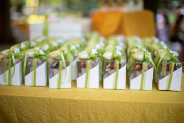 Elegant wedding favors bomboniere arranged on a table at a reception. Each box is decorated with ribbons and flowers, containing traditional sugared almonds.